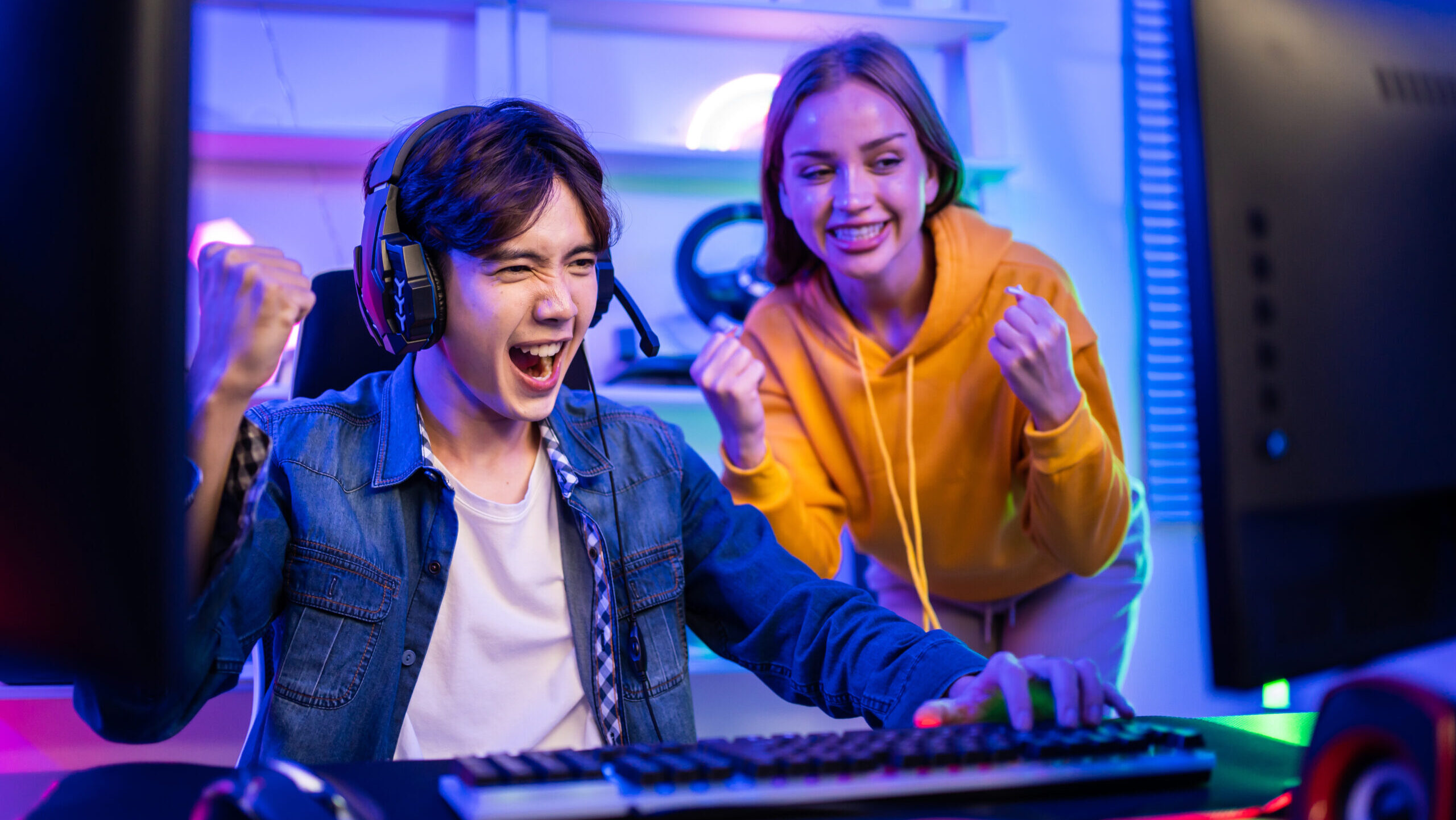 Caucasian Esport couple gamer playing online video game on computer. Handsome man gaming player feel happy and excited, enjoy technology broadcast live streaming while plays cyber tournament at home