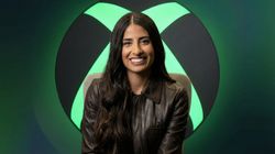 Asha Sharma, CEO da Xbox, sentada em frente ao logo da Xbox iluminado